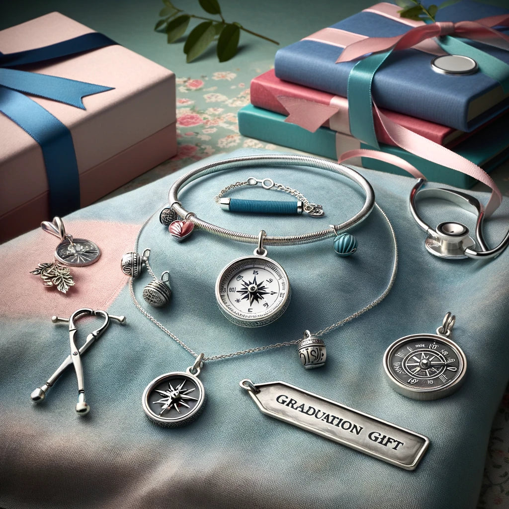 Display of Magpie Gems' graduation-themed sterling silver jewellery, featuring a compass necklace, sophisticated bracelet, stethoscope charm, and personalized bookmark on a fabric with brand colours.