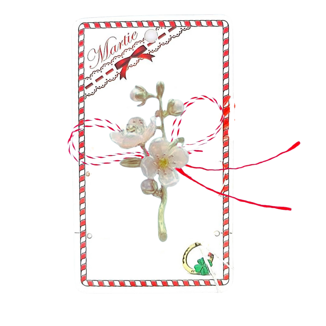 Ivory Cherry Blossom Martisor Brooch displayed on a decorative card with red and white accents, featuring delicate ivory cherry blossoms with golden details and the traditional red and white Martisor bow, symbolising spring and renewal.