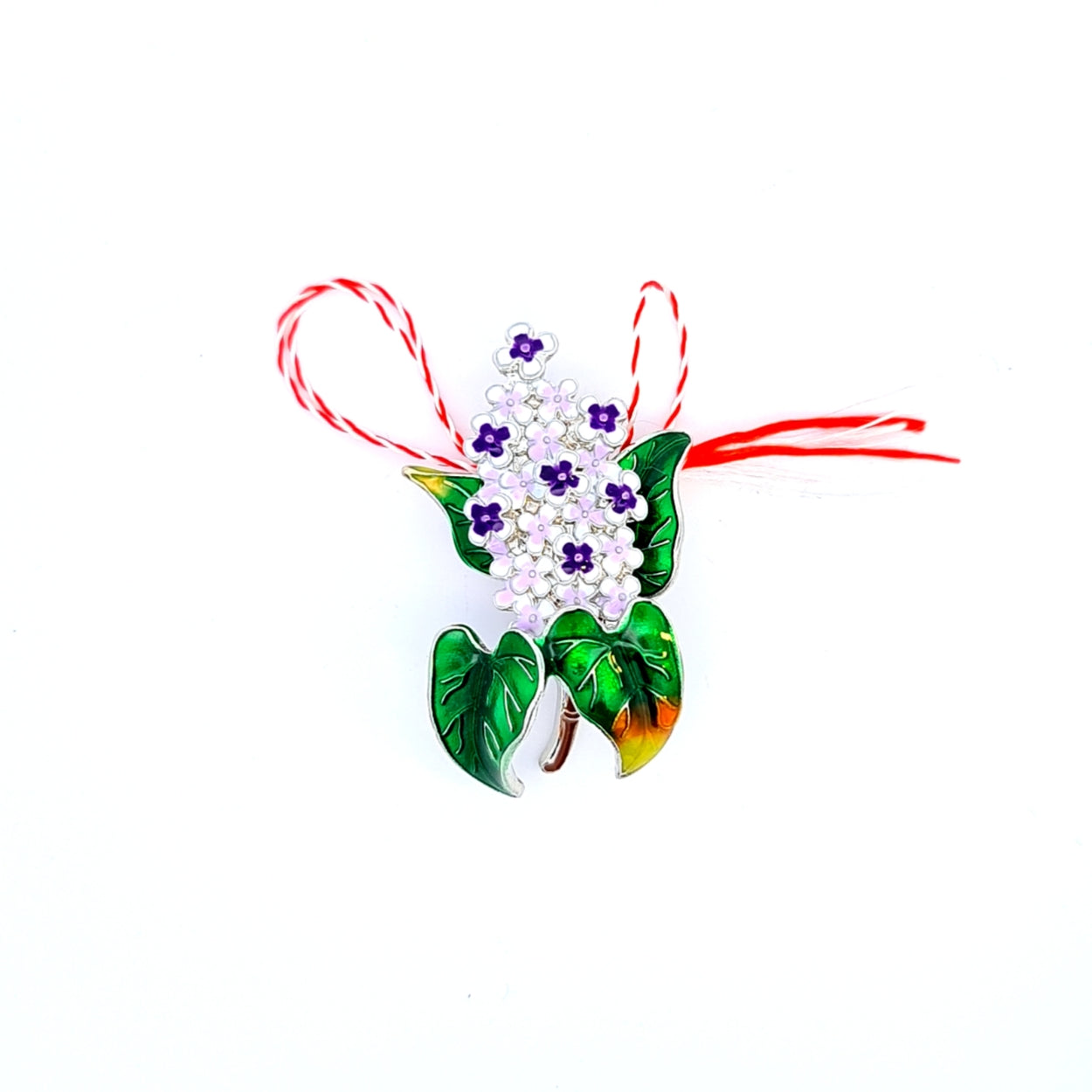 Lilac Flower Martisor Brooch on a white background, featuring delicate purple blossoms and vibrant green leaves with golden accents, symbolising spring and renewal, paired with the traditional red and white Martisor bow, by Magpie Gems in Ireland.