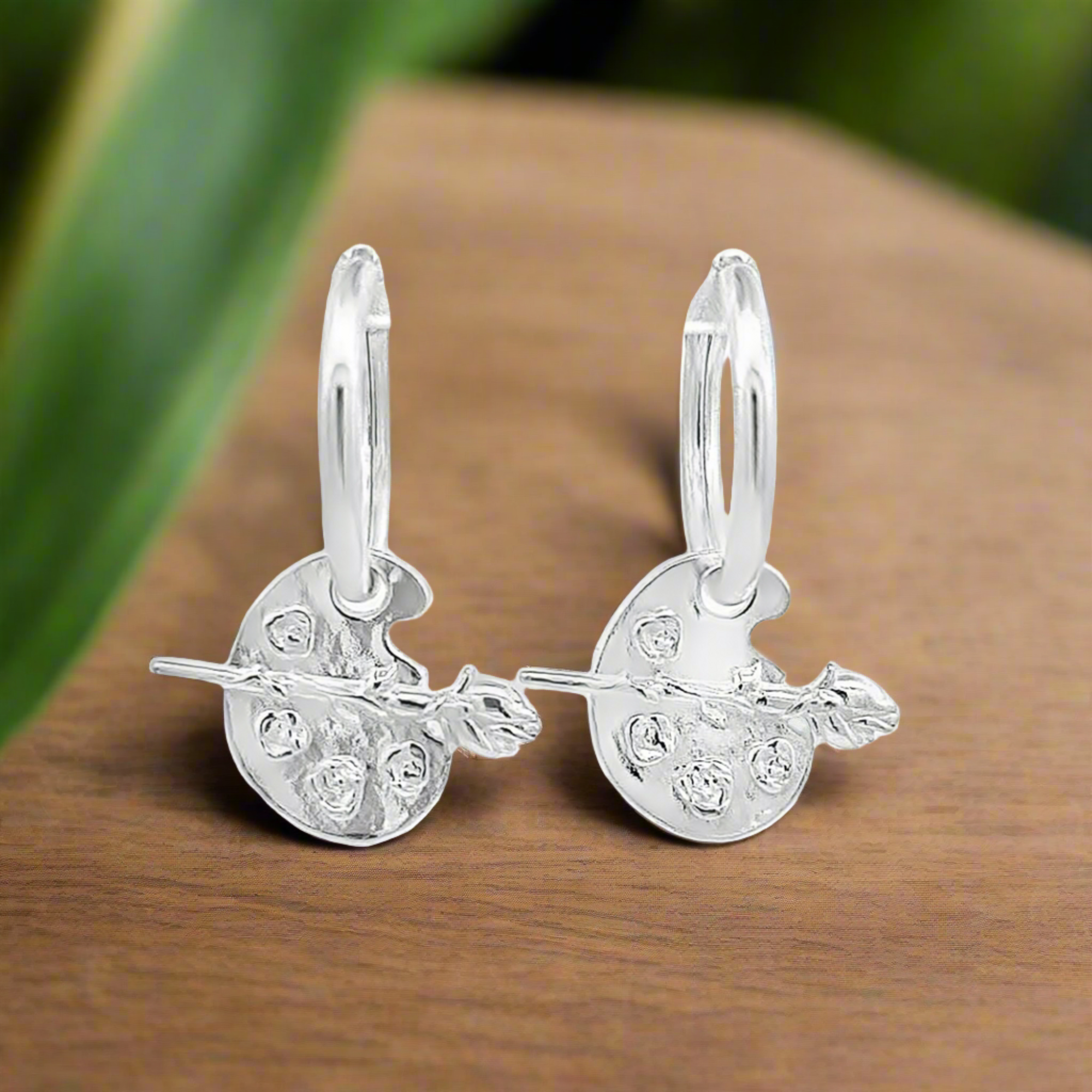 Pendientes de aro con dije de rosa sobre paleta de pintura de la musa del artista | Plata de ley 925