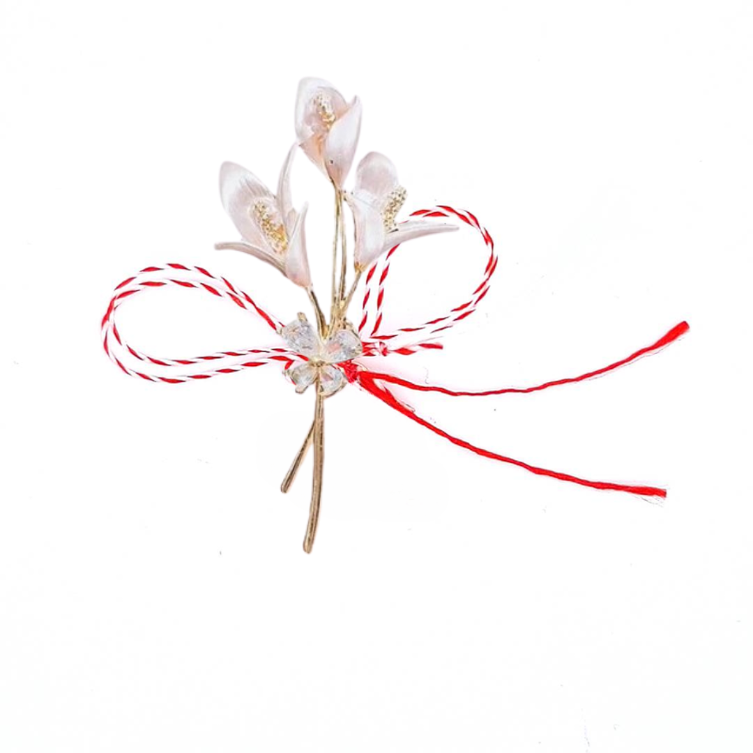 Soft Pink Lily Bouquet Martisor Brooch on a white background, showcasing elegant pink lily blossoms with golden accents and a sparkling crystal bow, paired with the traditional red and white Martisor bow to symbolise spring and renewal.