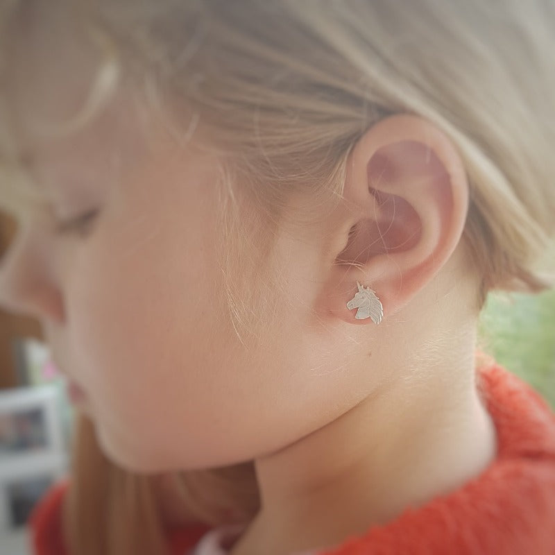 Young girl wearing Unicorn Silver Stud Earrings, showcasing their size and elegance