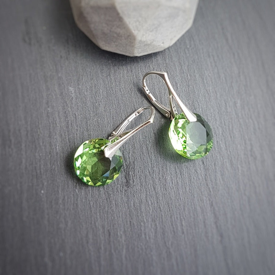 Round Peridot crystal drop earrings with leverback hooks, displayed on a dark slate background. Personalised Silver Jewellery Ireland by Magpie Gems