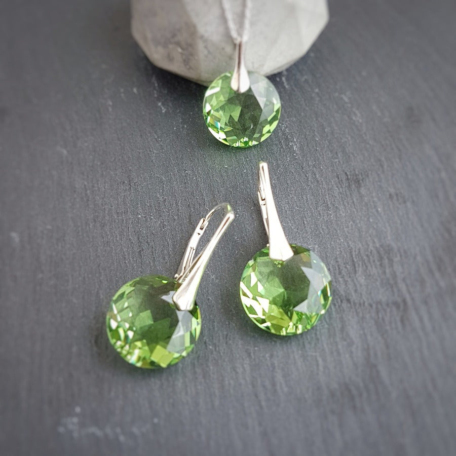 Peridot jewellery set featuring a pendant and matching drop earrings with sterling silver hooks, displayed on a dark slate background - Personalised Silver Jewellery Ireland by Magpie Gems