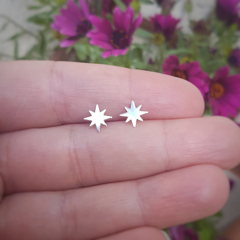 Hand holding Winter Star Sterling Silver Stud Earrings showing 8.5mm star design size. Christmas Star stud earrings in sterling silver for sensitive ears by Magpie Gems Cork Ireland